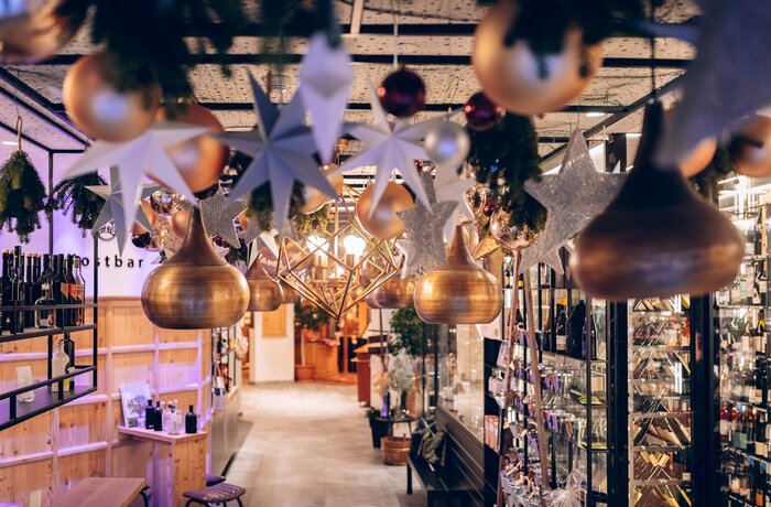 Weihnachtsdekoration mit goldenen Kugeln, Sternen und Tropfen hängt von der Decke eines Geschäfts