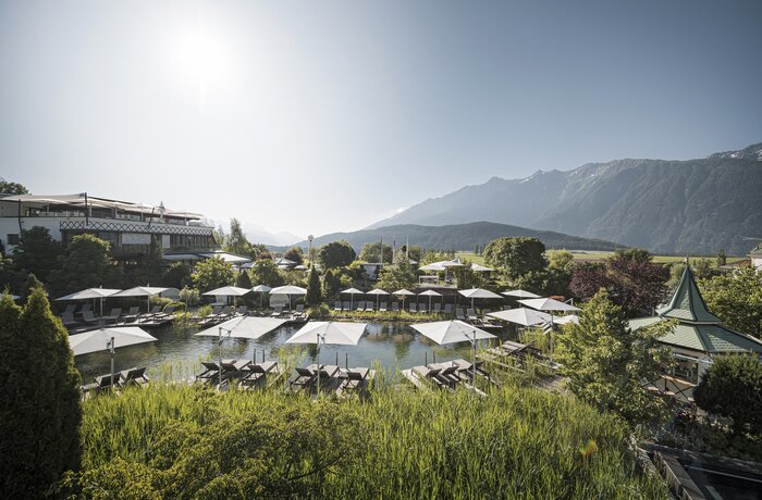 Naturpool im Alpenresort Schwarz mit Liegebereich und Blick auf die Tiroler Berglandschaft