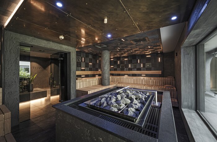 Dark sauna with stone oven and wooden benches