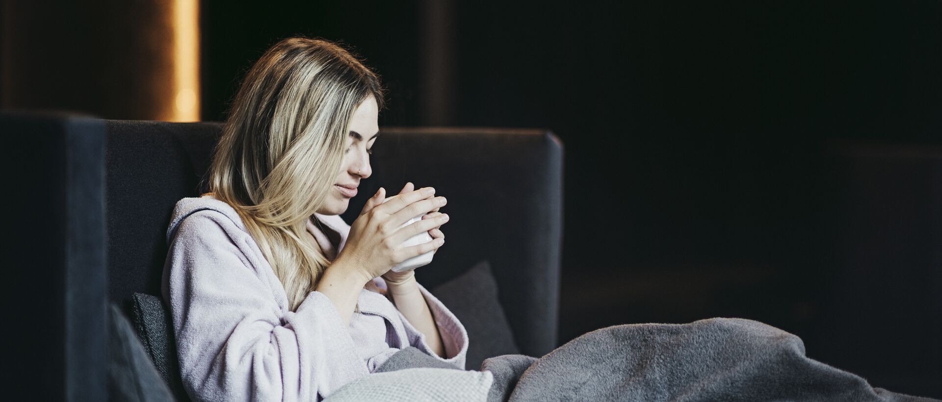 Woman relaxing in a wellness hotel with a cup of tea in a cozy lounge atmosphere.