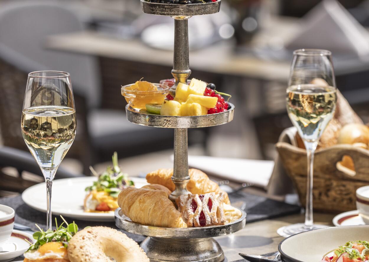 Elegant brunch with pastries, fruit, and two glasses of sparkling wine in a stylish setting.
