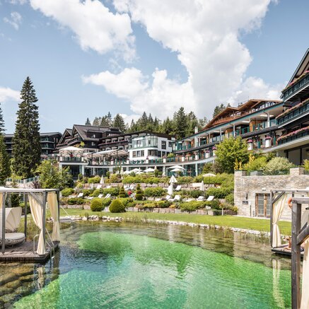 Alpin Resort Sacher Seefeld mit Pool und begrünten Terrassen an einem sonnigen Tag