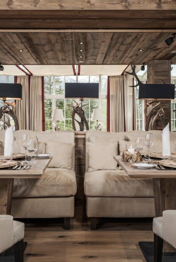 Restaurant mit Holzbalken, gedeckten Tischen und beigen Sofas