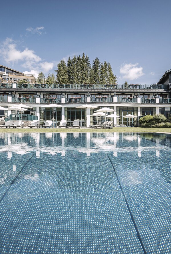 Hotelanlage mit Pool im Vordergrund und bewaldeten Hügeln im Hintergrund