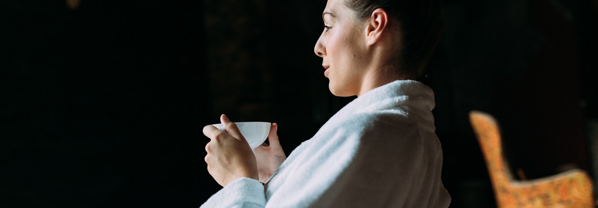 Frau im Bademantel hält eine Tasse in der Hand