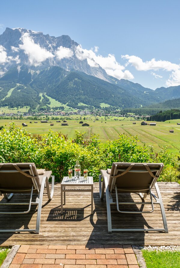 Zwei Liegen mit traumhaftem Blick auf eine weite Berglandschaft und grüne Wiesen.