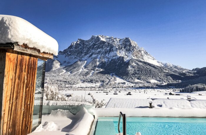 Winter saltwater pool with a view of the snow-capped Zugspitze under a blue sky