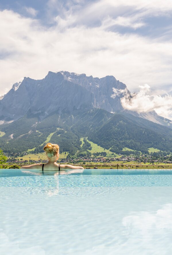 Frau im Pool vor Bergpanorama mit Wolkenhimmel
