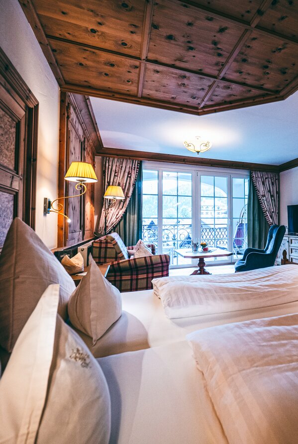 Gemütliches Hotelzimmer im alpinen Stil mit warmen Holzelementen und Balkonblick.