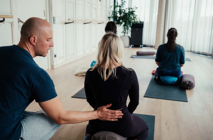 Ein Trainer unterstützt eine Gruppe bei einer Yoga- oder Entspannungsübung.