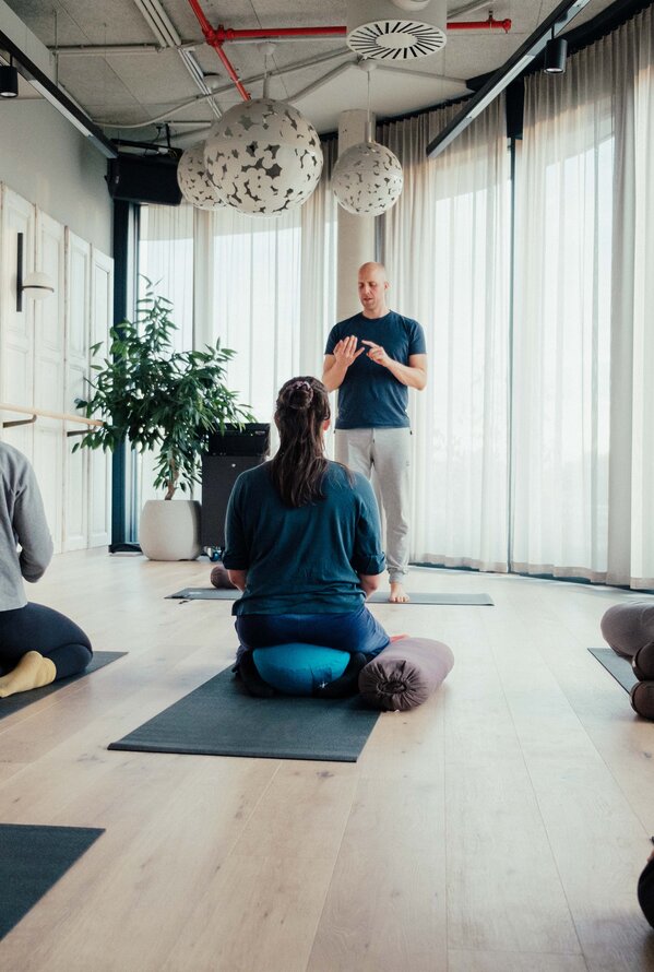 Ein Trainer unterstützt eine Gruppe bei einer Yoga- oder Entspannungsübung.