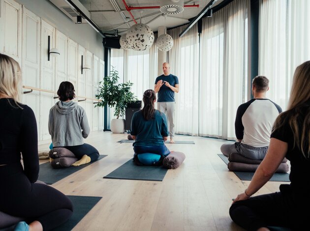 Ein Trainer unterstützt eine Gruppe bei einer Yoga- oder Entspannungsübung.