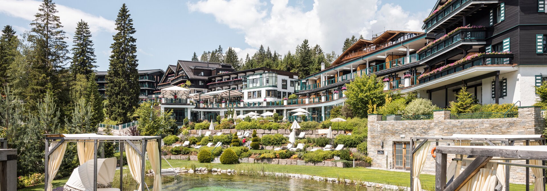 Alpin Resort Sacher Seefeld mit Pool und begrünten Terrassen an einem sonnigen Tag