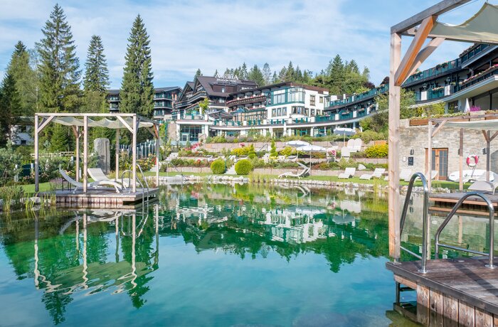 Astoria Naturbadesee mit Hotelanlage und Spiegelung im Wasser
