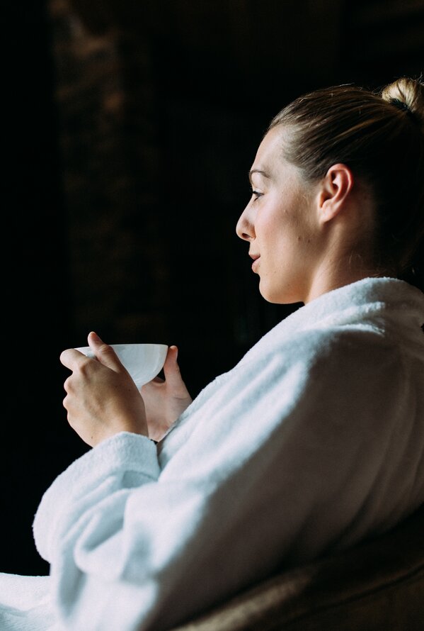 Woman in bathrobe holding a cup in her hand