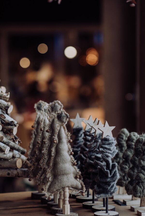 Dekorative Miniatur-Weihnachtsbäume vor dunklem Hintergrund mit Bokeh