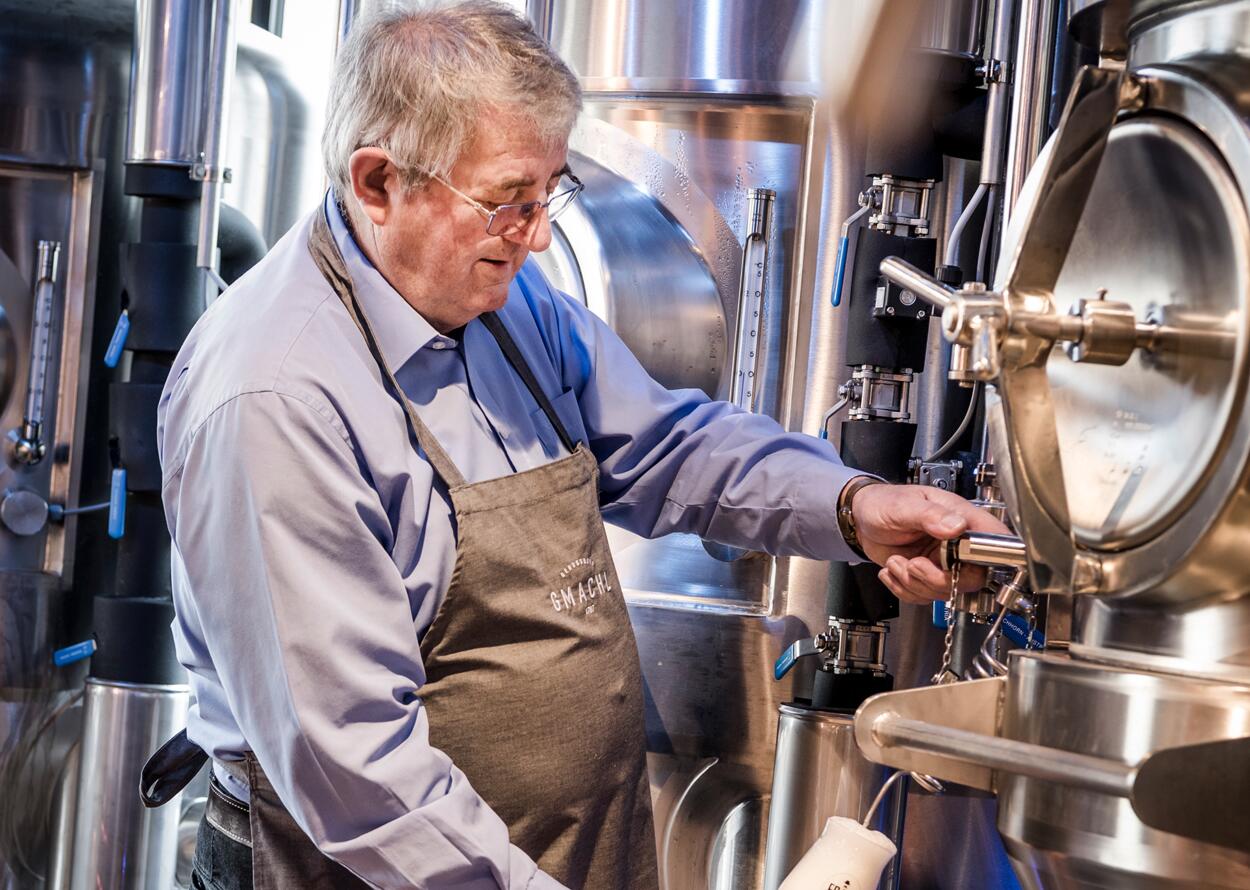 Braumeister bei der traditionellen Bierherstellung in moderner Brauerei mit frisch gezapftem Bier.