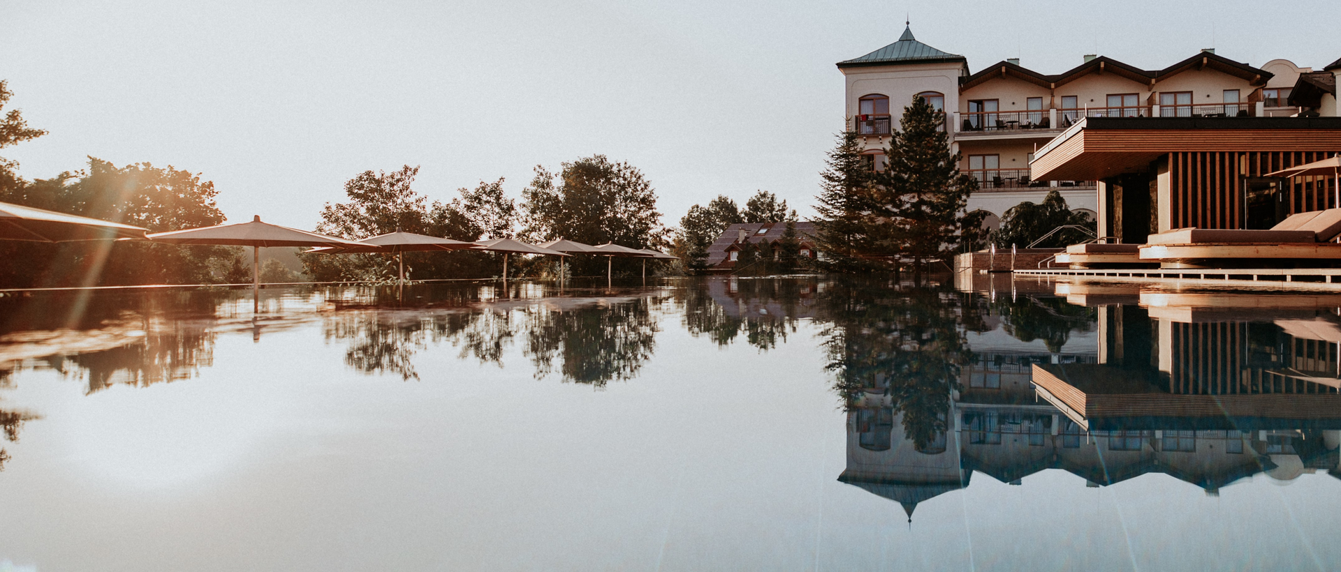 A calm pool reflects a hotel and the evening sky.