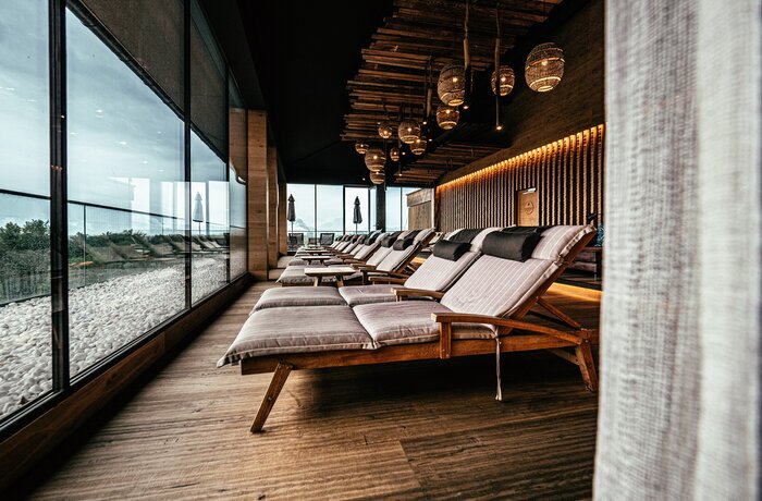 Spa-Bereich mit Liegen, großen Fenstern und dekorativer Deckenbeleuchtung