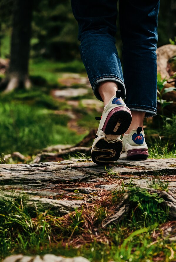 Füße in Turnschuhen gehen auf einem Waldweg