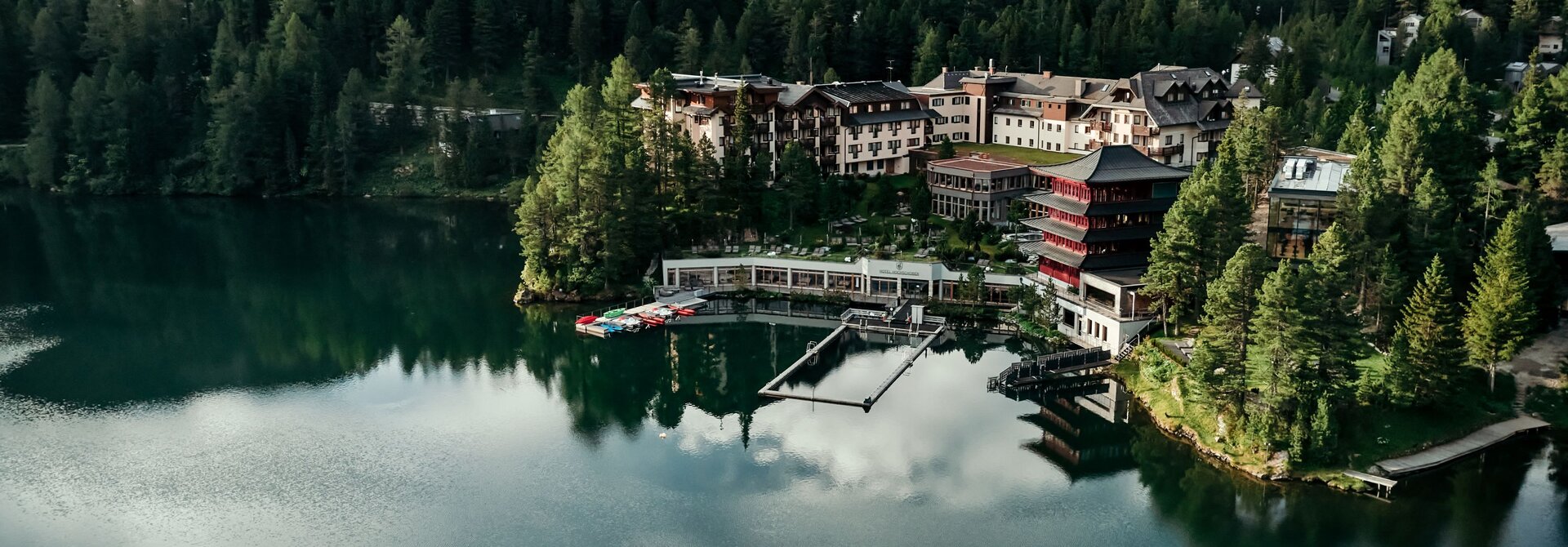 Hotelanlage am See, umgeben von Wald und Bergen