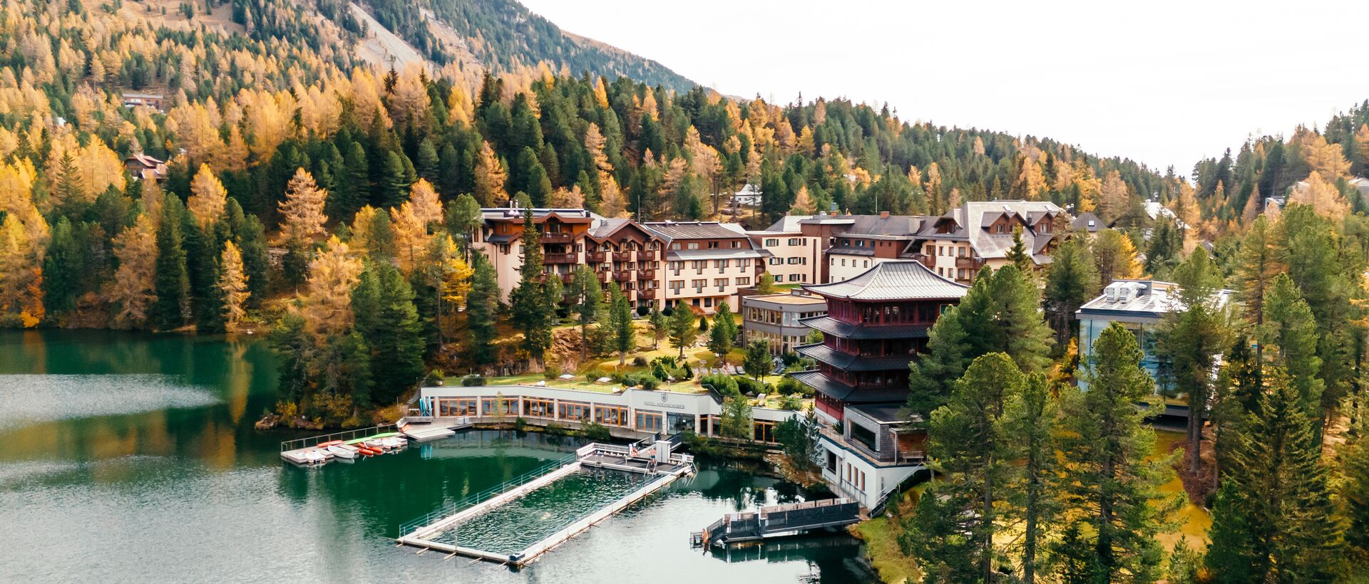 Ein idyllisches Resort liegt eingebettet zwischen herbstlichen Wäldern und einem ruhigen Bergsee.