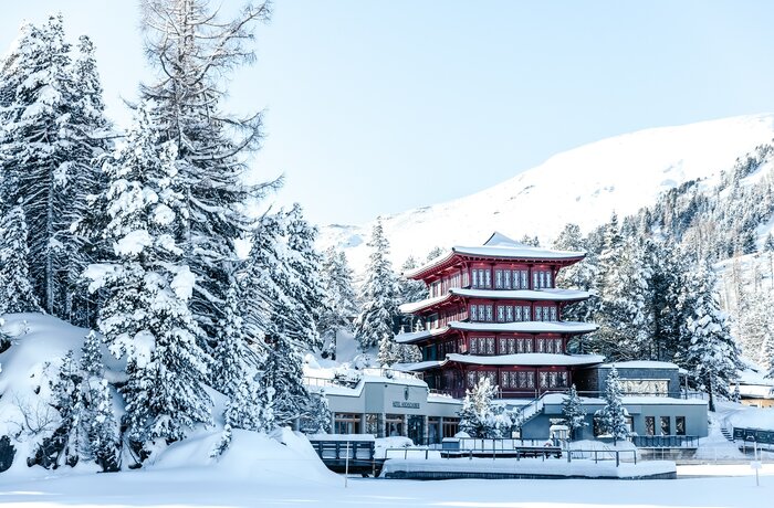 Chinaturm des Hotel Hochschober im Schnee mit rotem Pagoden-Turm vor verschneiter Berglandschaft