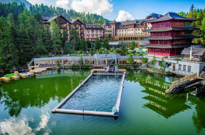 Hotelanlage am See mit Schwimmbad, traditionellen Holzhäusern und asiatischem Pavillon