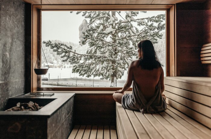 Woman in sauna looking at snowy landscape