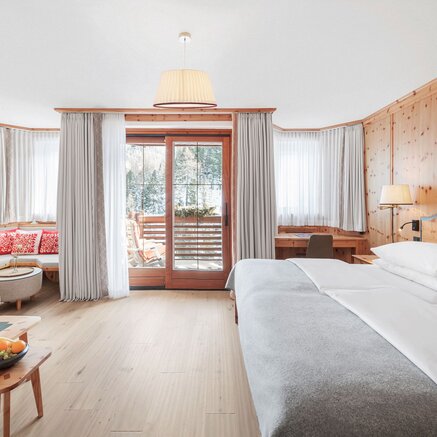 Bright pine room with double bed and balcony view.