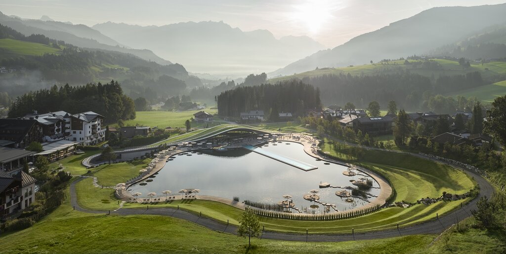 Panorama des Krallerhofs im Sommer mit See, Liegeflächen und Bergen im Hintergrund