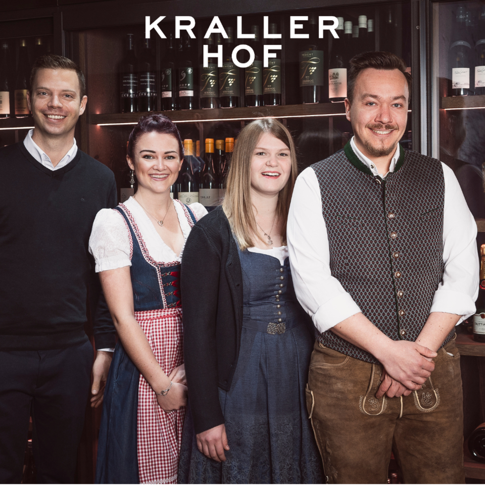 Vier Personen vor Weinregal mit Schriftzug Krallerhof