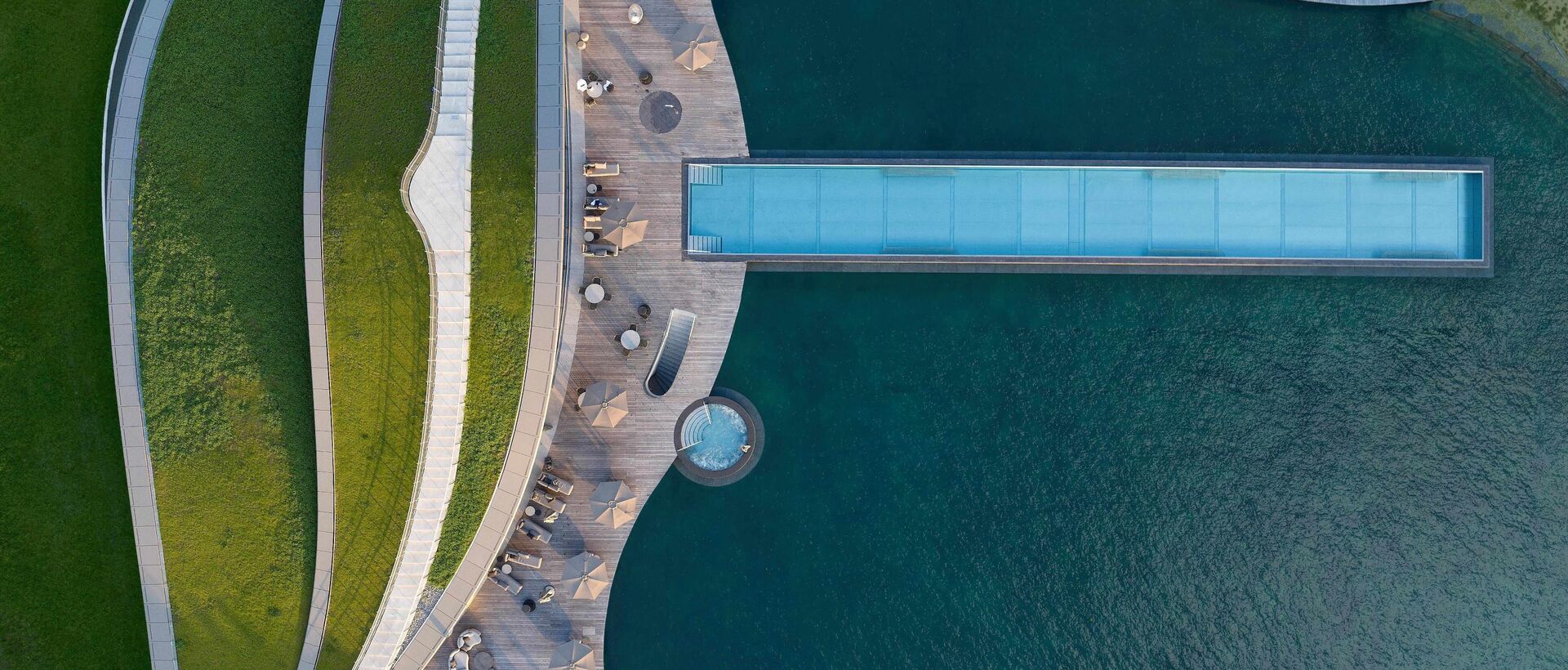 Luftaufnahme eines modernen Wellnessbereichs mit elegantem Infinity-Pool und harmonischem Design.
