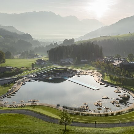 Panorama des Krallerhofs im Sommer mit See, Liegeflächen und Bergen im Hintergrund