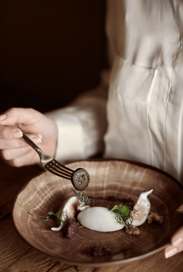 Fine-Dining-Gericht im Krallerhof kunstvoll angerichtet auf einem Holzteller