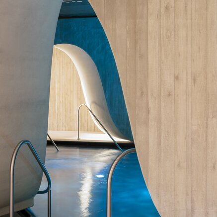 Interior view of a swimming pool with curved walls and blue water