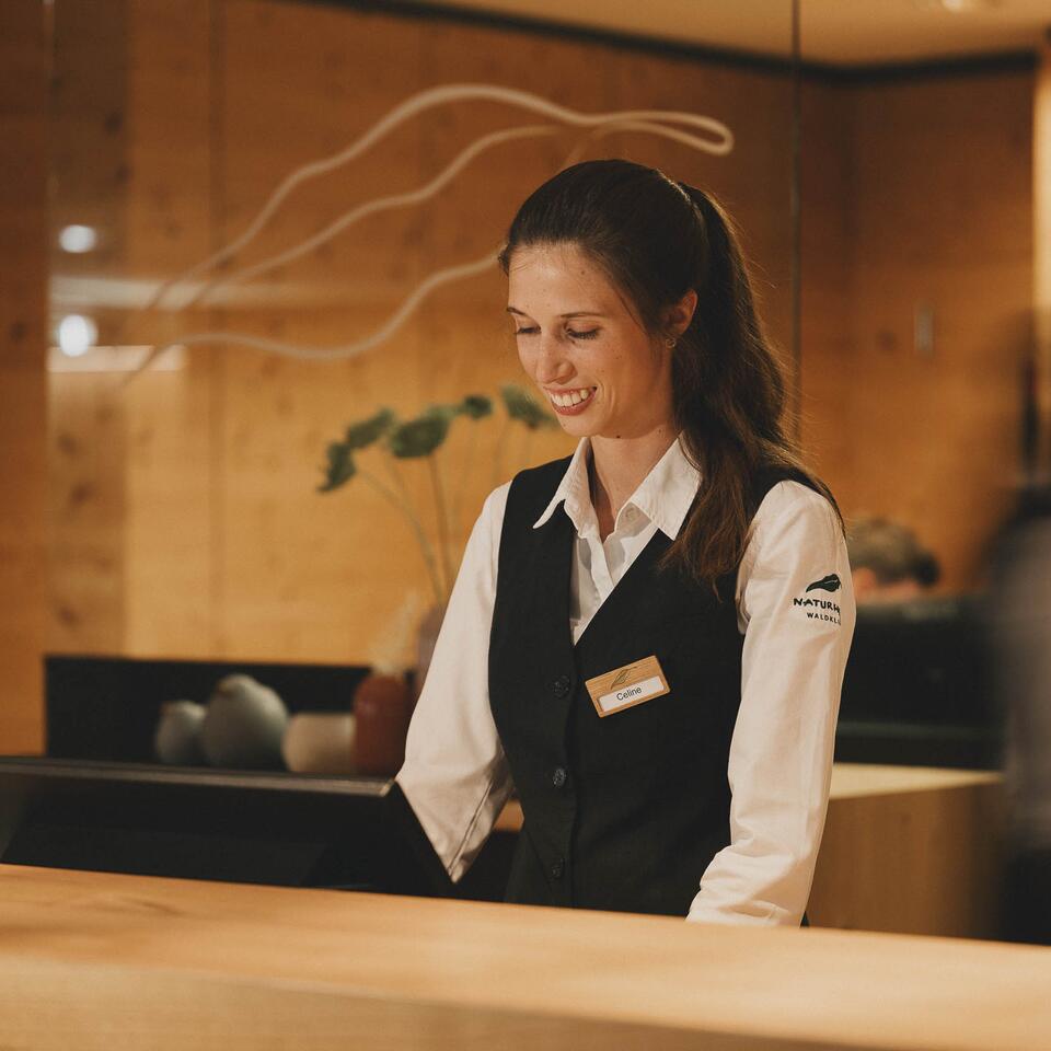 Freundliche Hotelangestellte mit Namensschild am Empfang