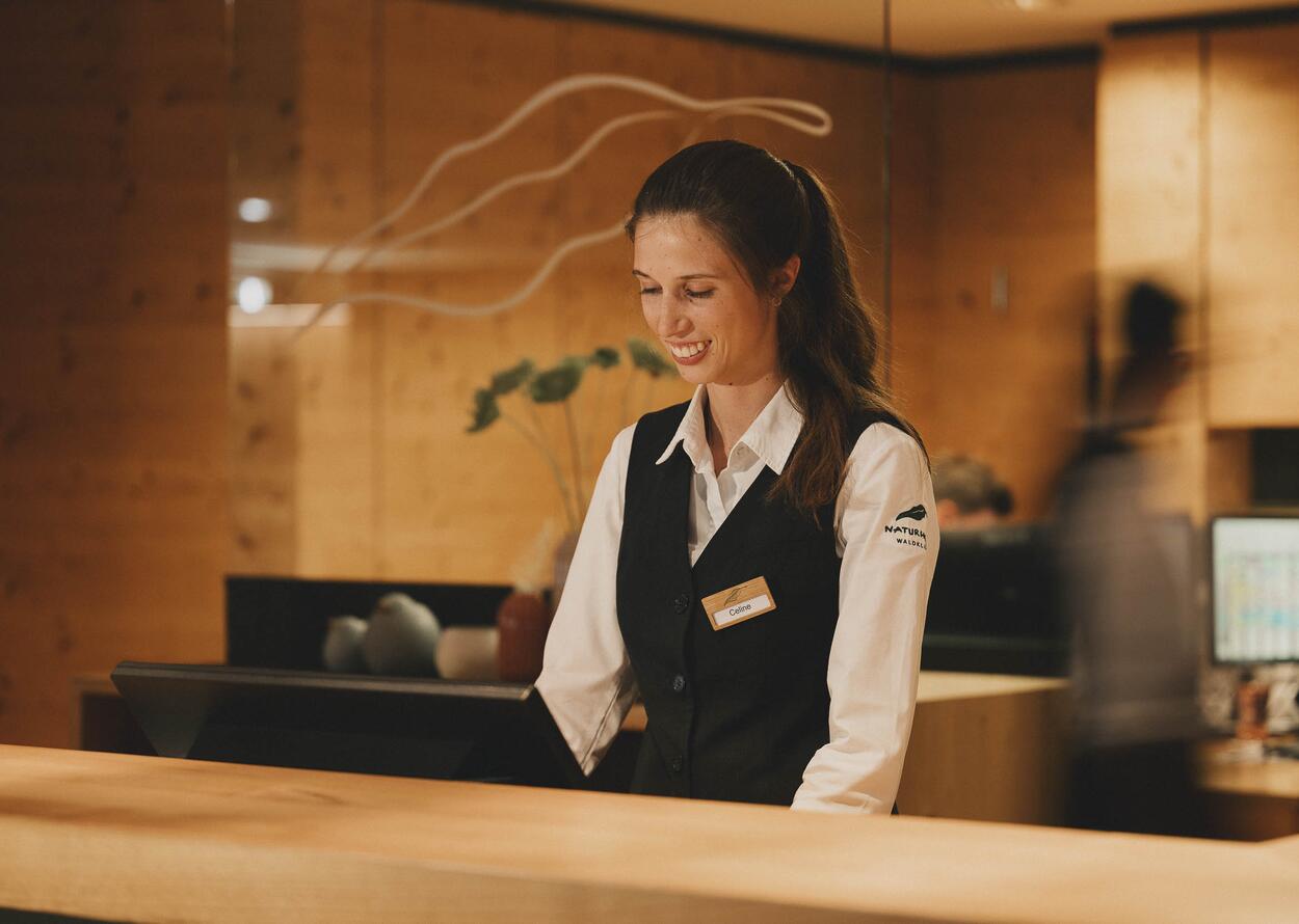 Freundliche Hotelangestellte mit Namensschild am Empfang