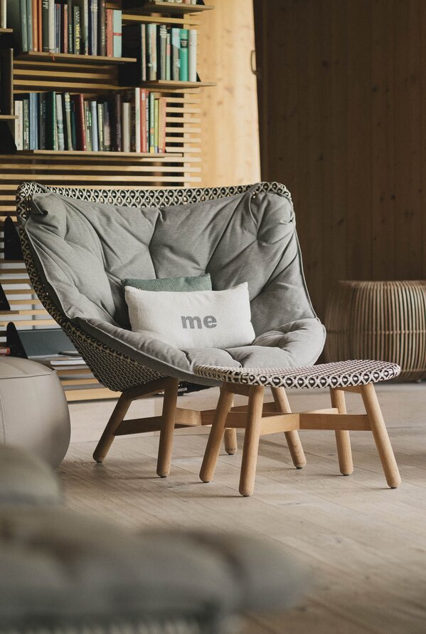Gemütlicher Ruhebereich mit Sesseln, Bücherregal und warmer Holzoptik.