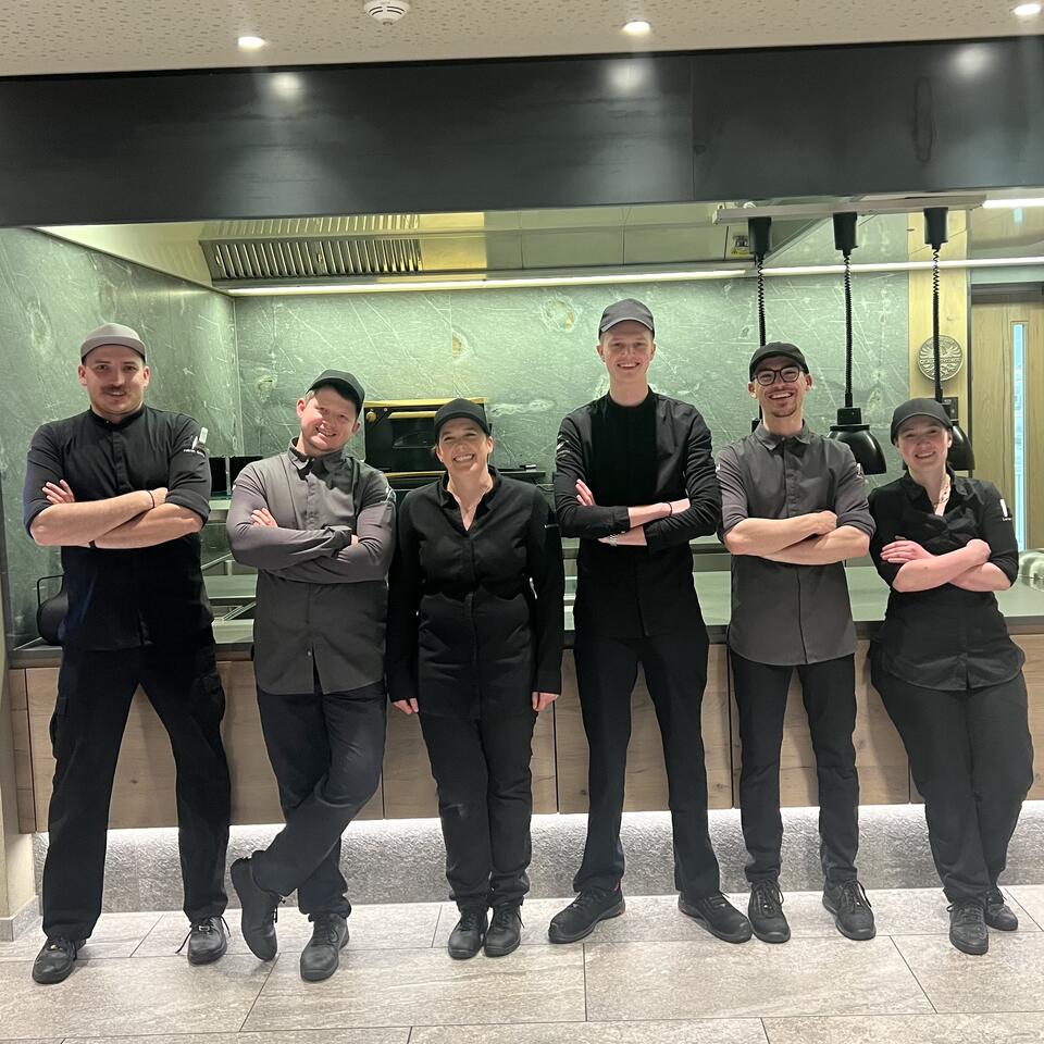 Das Küchenteam präsentiert sich motiviert und professionell in der modernen Restaurantküche.