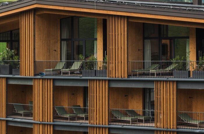Modernes Hotelgebäude mit Balkonen vor Berglandschaft.