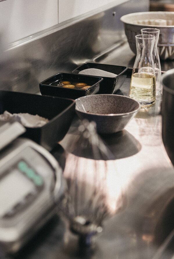 Stainless steel table with bowls, bottles and a scale in a kitchen