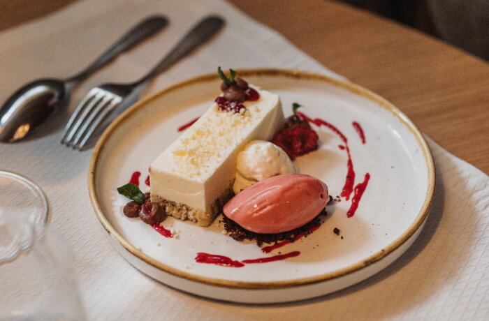 Ein elegant angerichtetes Dessert mit Eis und Beeren steht auf einem Restauranttisch.