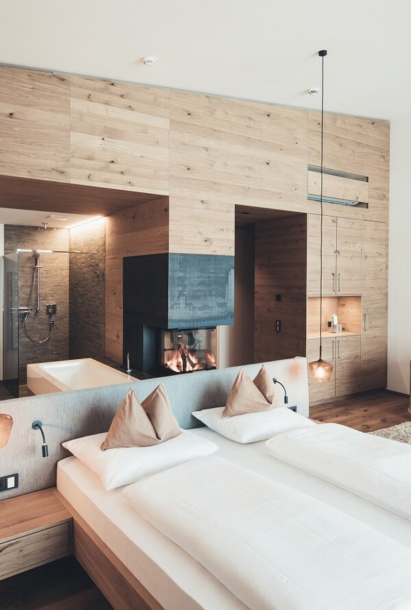 Bright hotel room with double bed, fireplace and seating area