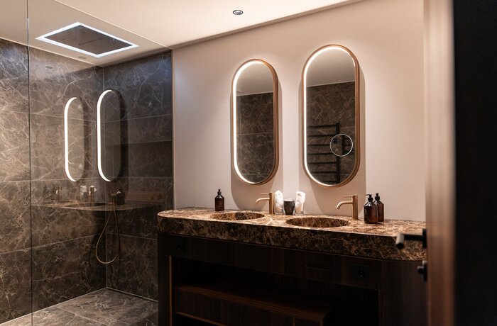 Modern bathroom with two sinks and oval mirrors with lighting