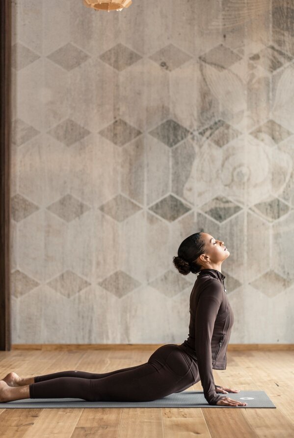 Frau macht eine Yogaübung in einem ruhigen Wellnessstudio mit einer Buddha-Statue.