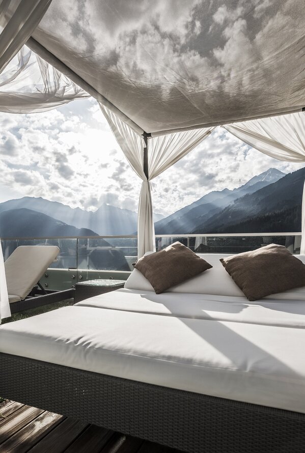 Daybeds im Wellnessbereich des Stock Resort mit Blick auf die Tiroler Alpen