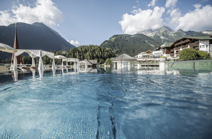 Außenpool im Stock Resort mit Daybeds und Blick auf die Tiroler Alpen