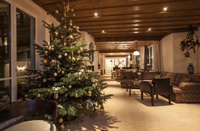 Lounge mit Weihnachtsbaum, dunklen Möbeln und Holzbalkendecke