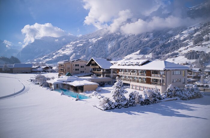 Winterlandschaft mit schneebedeckten Häusern und Bergen im Hintergrund